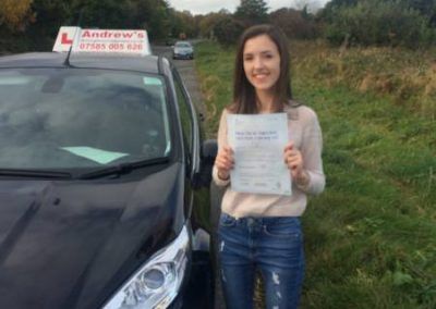 Emily standing by driving school car with driving test pass
